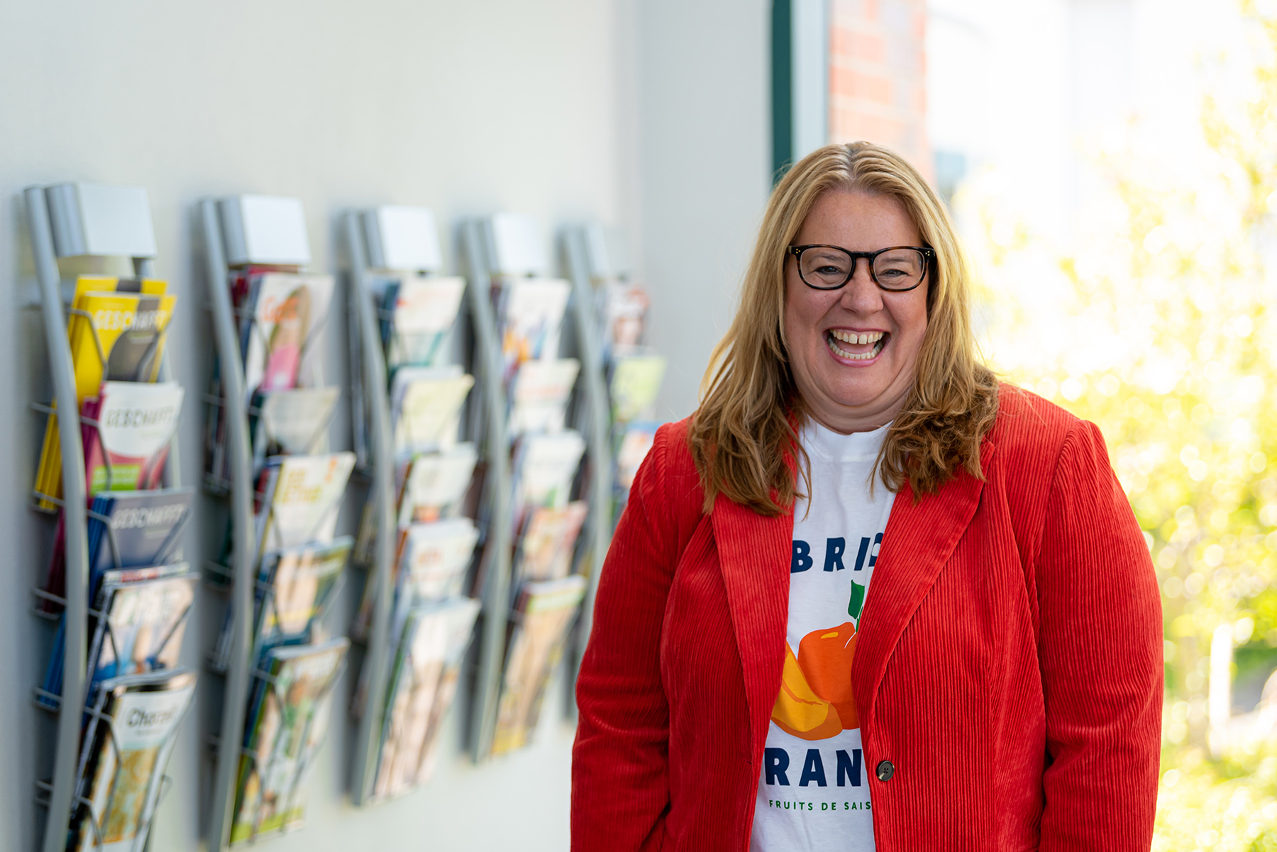 Lachende Frau vor Zeitschriftenständer