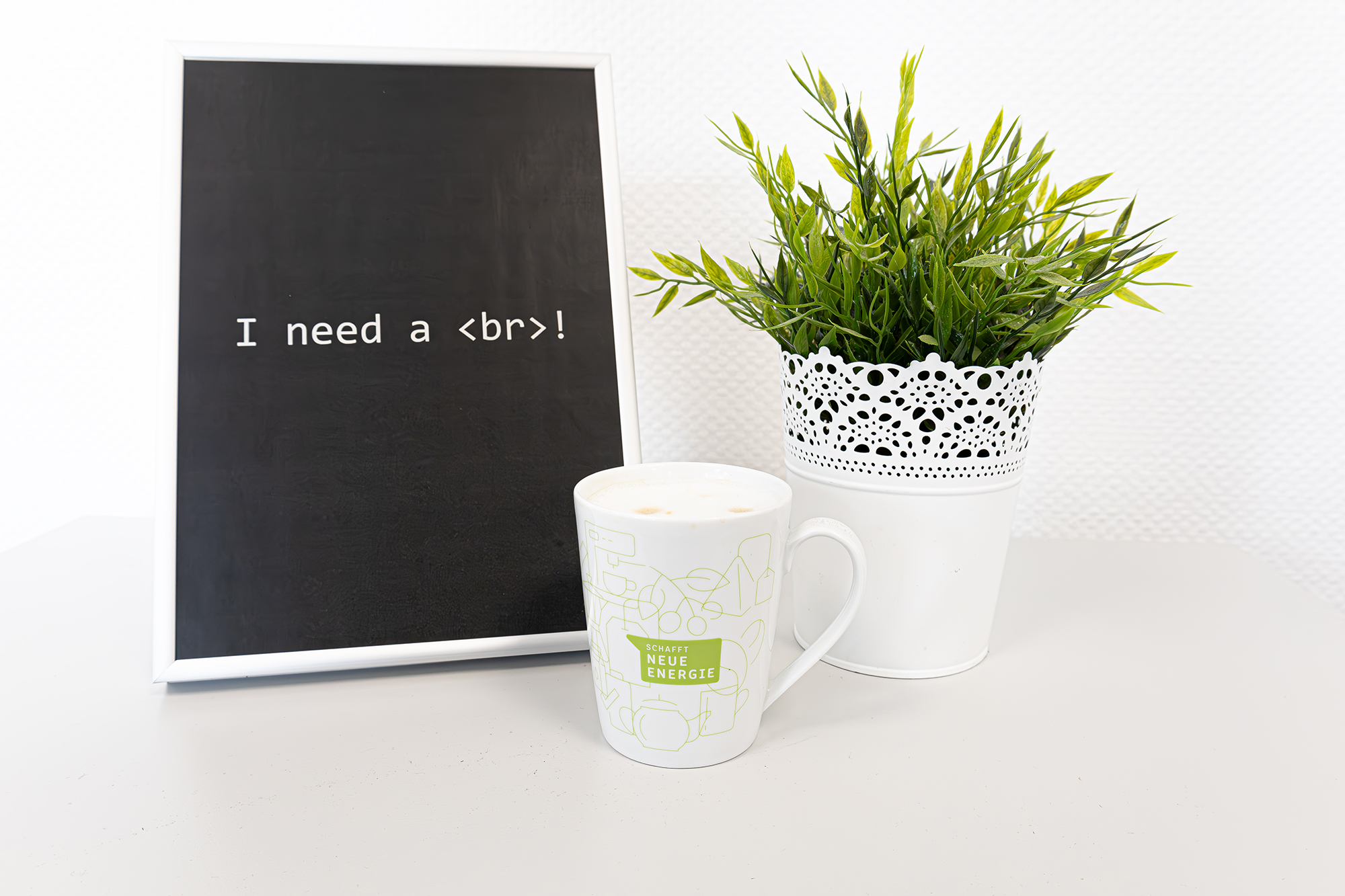 Schwarzes Bild mit dem Hinweis "Need a break". Davor steht eine Kaffeetasse und daneben eine Zimmerpflanze.